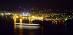 un notturno della baia di portoferraio con un traghetto che passando lascia una scia luminosa.