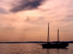 Foto fatta al tramonto sul lago di garda. Sul pelo dell'acqua, all'orizzonte, una lama di luce esalta las siluetthe della barca.