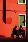 Due signore anziane lavorano a maglia all'aria aperta di una strada di Burano