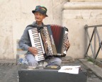 busker in piazza con fisarmonica e valigia