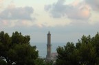 La lanterna di Genova che spunta dai pini marittimi tipici della riviera mediterranea