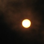...foto del sole scattata in pieno giorno attraverso una nube nerissima provocata da un incendio di un deposito di pneumatici