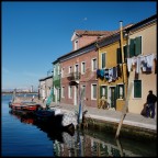 Estremo lembo  di Burano. 
In fondo si vede l' isola di Torcello con le chiese di S. Maria Assunta con il suo campanile, e S. Fosca.
Oltre l' isola, le alpi innevate