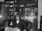 Il noto collezionista di libri Umberto Baccolo fotografato davanti ad una delle sue librerie