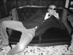 Umberto Baccolo in una provocatoria posa sull'antico divano rosso del suo salotto