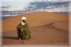 Un Touareg del deserto del Sahara si riposa al tramonto. Da vero uomo del deserto sa che che sedersi sulla sabbia non  una buona idea nemmeno quando la temperatura  gi scesa.