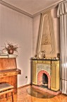 Interno con camino, piano, fiori secchi e bassorilievo.