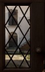 nel portone in legno a chiusura di un cortile di Desenzano del Garda, si apre questa finestra che lascia vedere il suo interno.
Peccato per il vetro ed i suoi fastidiosi riflessi.