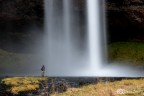 pescatore sotto la cascata di Seljalandsfoss in Islanda