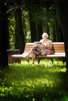 Anziana che legge un giornale su una panchina. Giornata di sole.